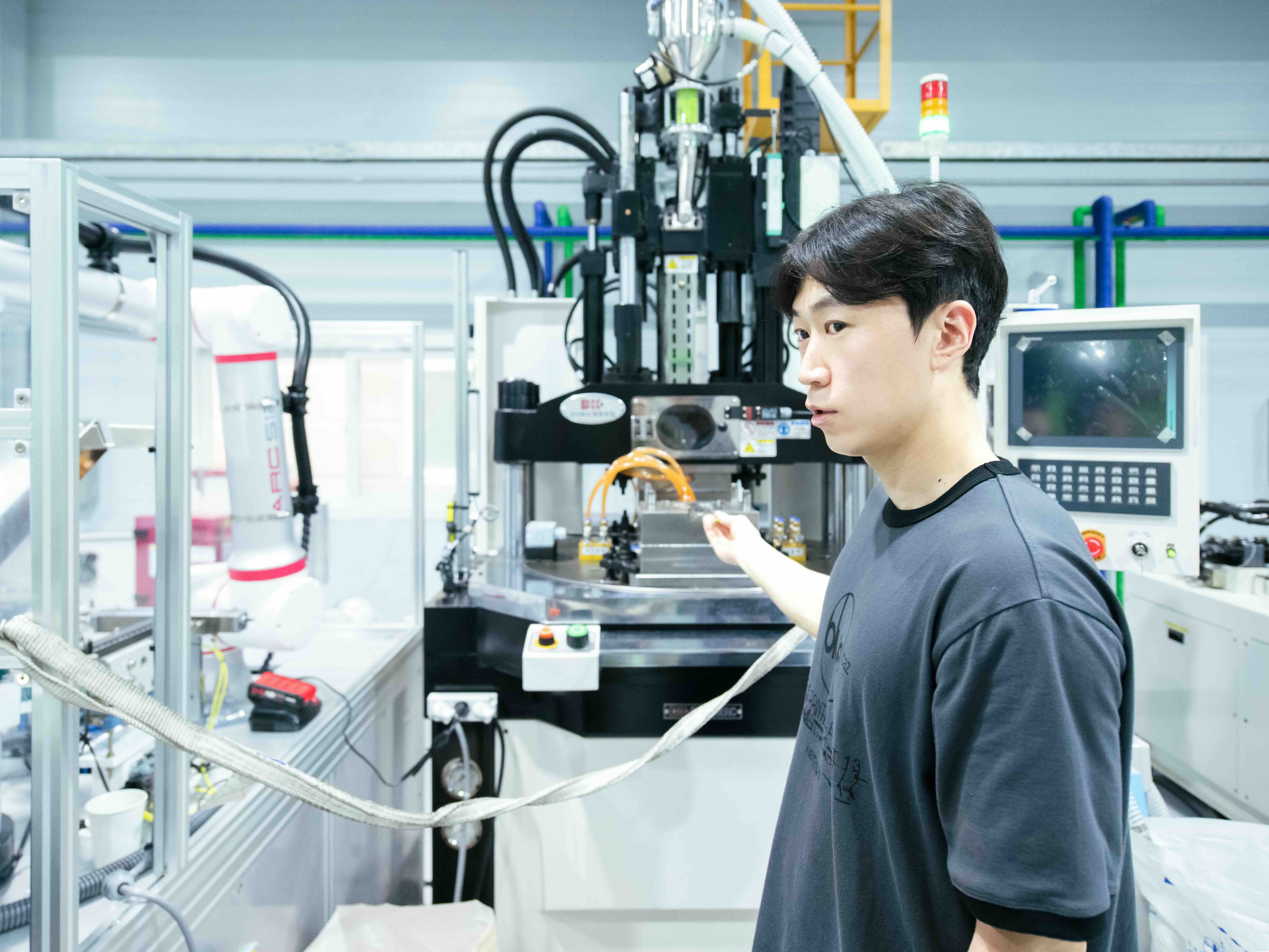 플라스틱 사출기를 설명하고 있는 최현택 매뉴팩처팀 리더. 자동화된 로봇 기계가 틀에 맞게 플라스틱 반죽을 주입하고 키링을 만들어낸다. ⓒ롱블랙